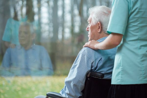Nurse assisting disabled senior man using wheelchair